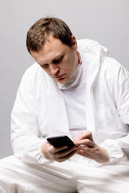 Tired doctor wearing mask and gloves at the hospital in coronavirus times checking his smartphone