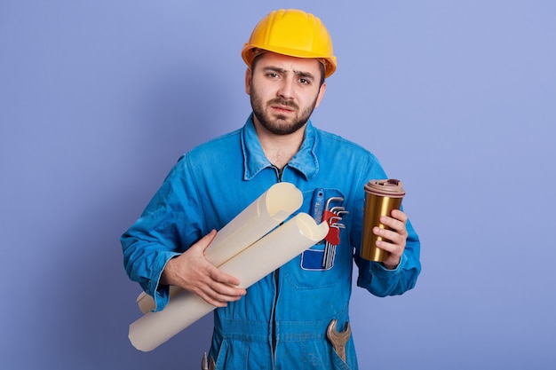 Tired engineer or foreman in protective yellow helmet and blue workwear