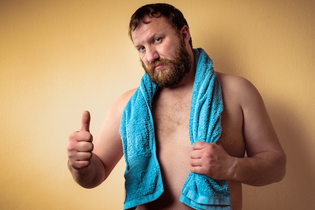 Tired and exhausted halfnaked bearded man after training showing thumbs up like