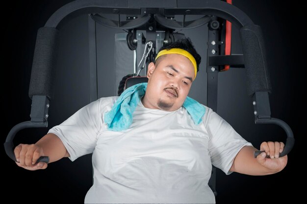 Photo tired fat man sitting on the exercise machine