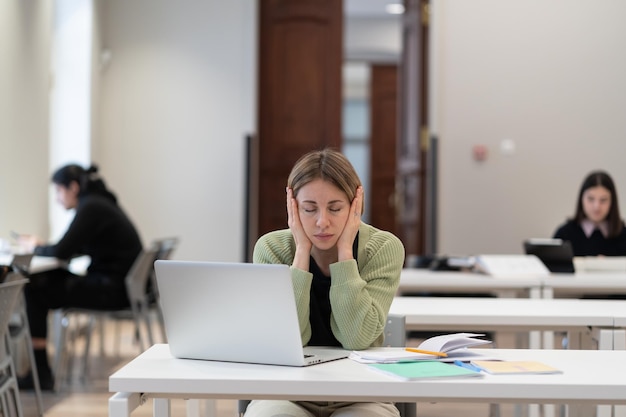 Studentessa matura stanca seduta in biblioteca che si sente immotivata a studiare per ottenere il secondo grado