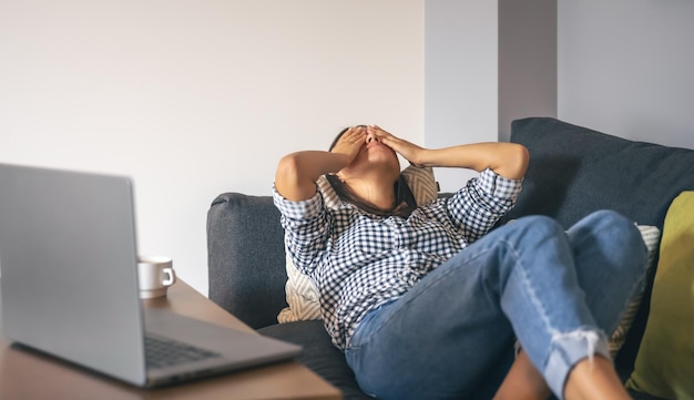 Tired from work young woman in front of a laptop