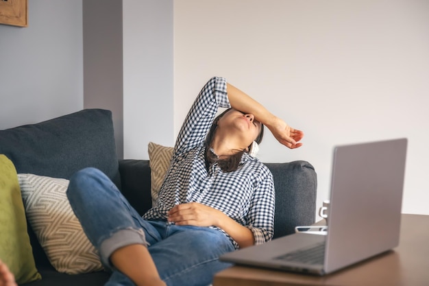 Tired from work young woman in front of a laptop