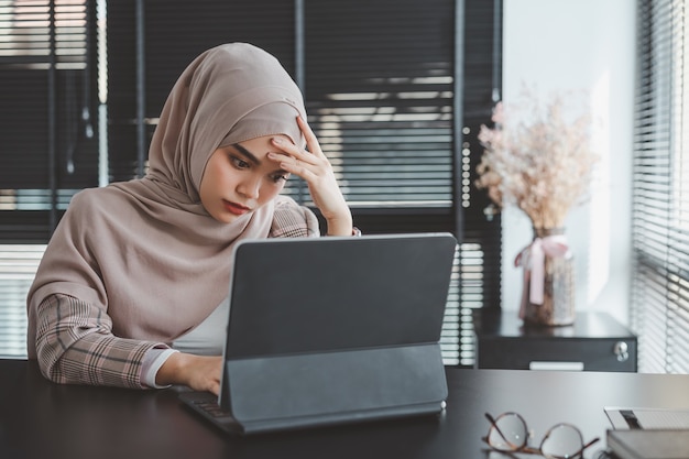 Усталая разочарованная молодая мусульманская бизнес-леди в коричневом хиджабе, чувствуя стресс, держась за голову руками, концепция провала бизнес-проблемы