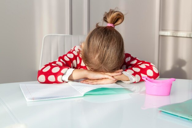 Photo tired girl fell asleep on school exercise book studying at home at her desk