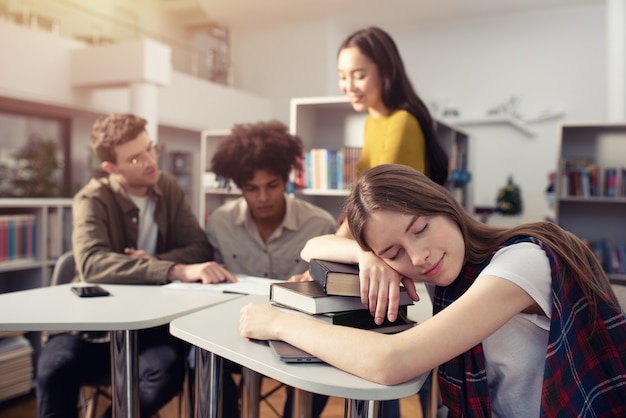 La ragazza stanca dorme sui libri durante un incontro con gli studenti