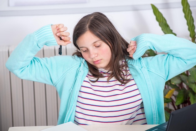 写真 テーブルの上の紙で伸びる疲れた女の子