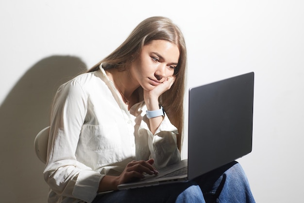 Фото Уставшая девушка с ноутбуком на белом фоне