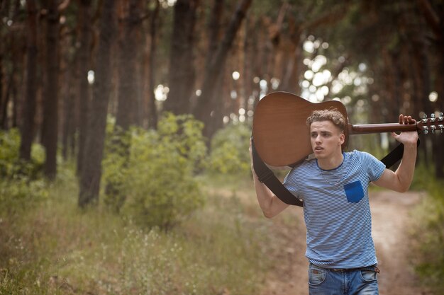 Photo tired guitarist man walk forest concept.