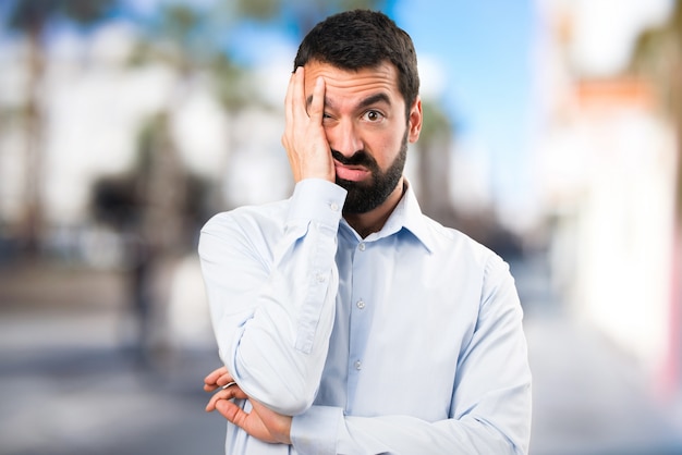 Tired handsome man with beard on unfocused background