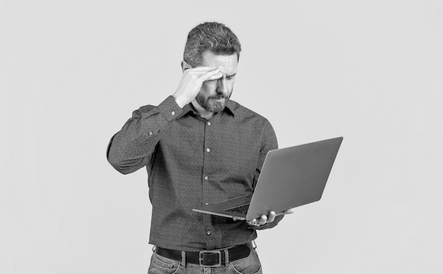 Tired handsome mature man businessman with beard working online on laptop office worker