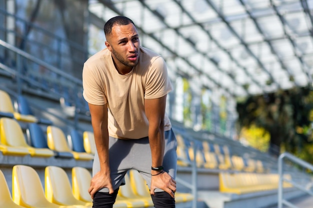 疲れたヒスパニック系アスリートジョギング後息を吐きながら晴れた日にスポーツをしている男性