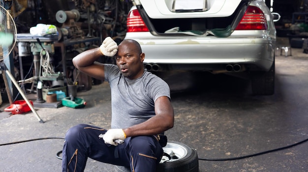 Photo tired hot wiping sweat african man car machanic worker working hard at auto car truck mechanic car service station workplace