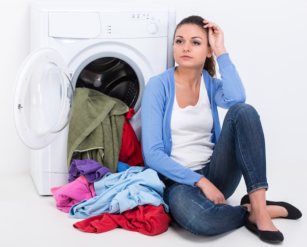 Tired housewife is doing laundry with washing machine.