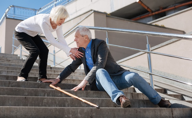 Photo tired ill calm man suffering from fatigue and telling his wife about pills while scared woman listening to him