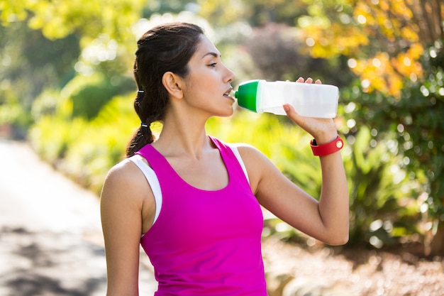 Tired jogger drinking water while taking a break