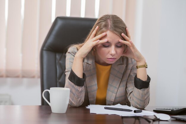 Capo stanco della signora che si siede al tavolo in ufficio