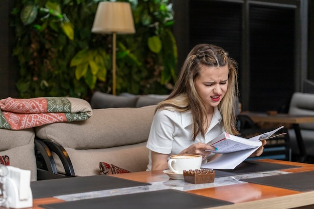 Signora stanca che si siede al ristorante e che legge il libro