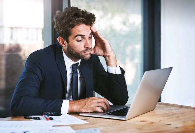 Photo tired laptop and stress businessman lazy with a headache in an office typing on a computer online or the internet sleepy burnout and depressed male corporate person writing a report or research