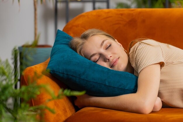 Tired lazy woman enjoy relaxing on home sofa resting napping after hard working day closed her eyes