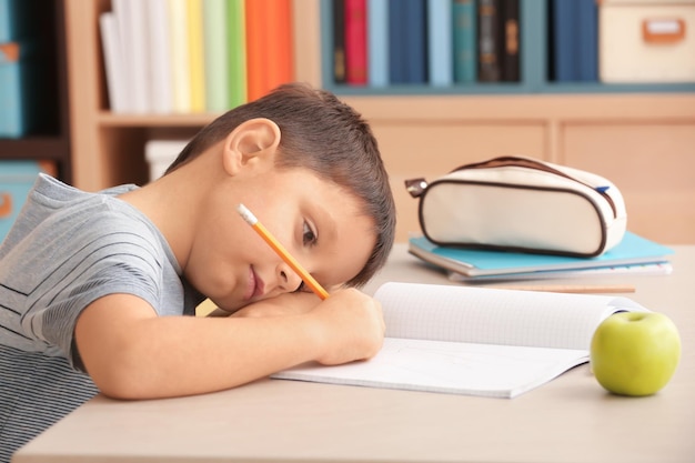 Tired little boy doing homework indoors