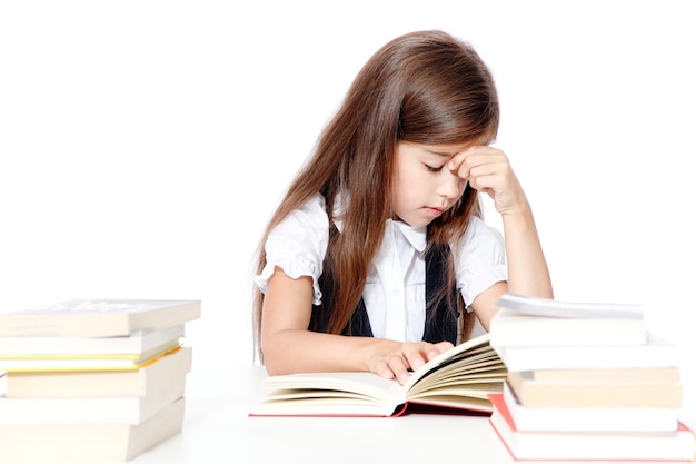 Tired little child girl sleeping on the desk at school.