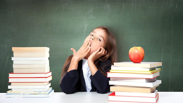 学校の机の上で寝ている疲れた小さな子供の女の子。