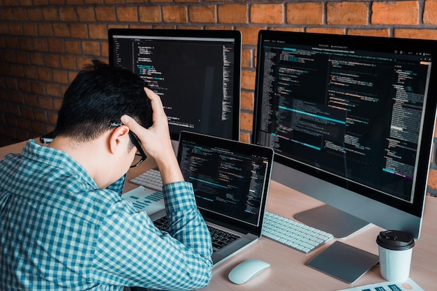 テーブルの上のラップトップとコンピューターで疲れた男