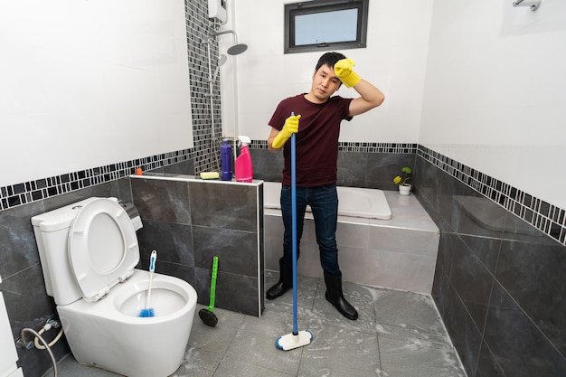 Photo tired man to cleaning the bathroom at home