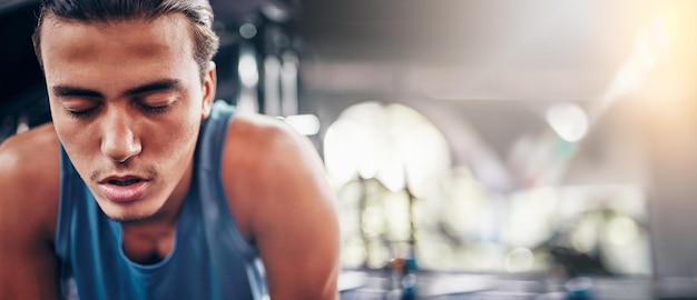 Tired man and gym for fitness workout and intense training against bokeh background space Exercise break and athletic male stop for breathing rest and exhausted from cardio sports or challenge