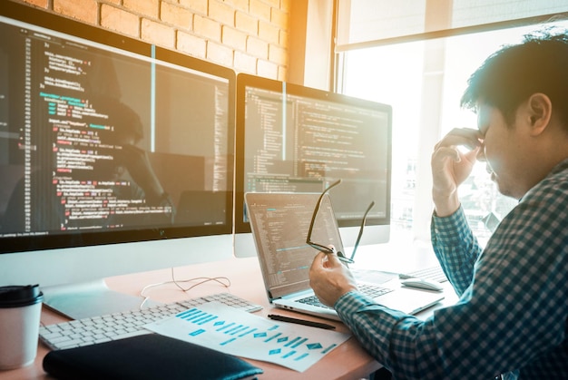 テーブルの上のラップトップとコンピューターで眼鏡を持っている疲れた男性