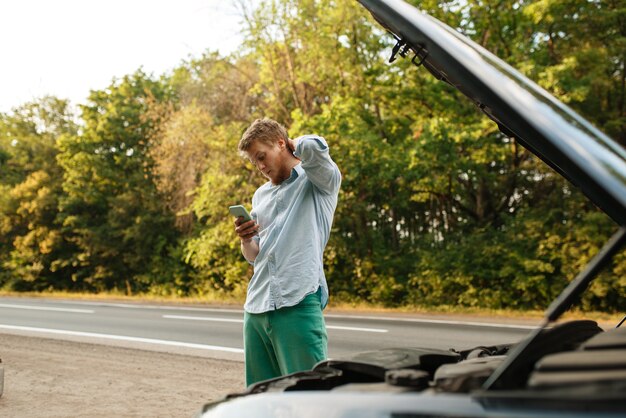 Tired man at opened hood fix problem with engine