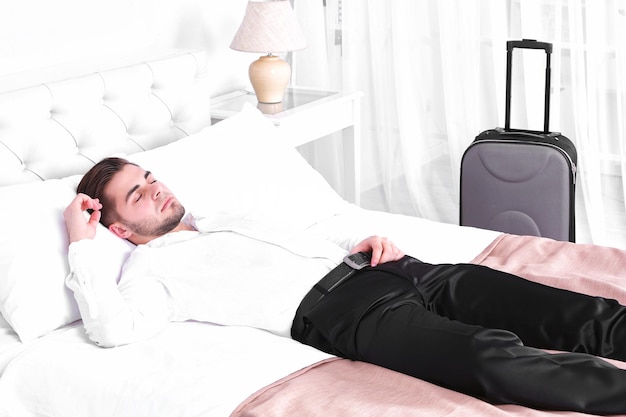 Tired man resting on bed in room