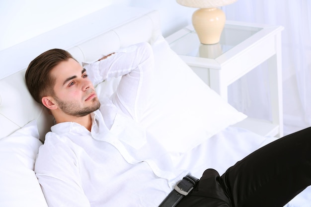 Tired man resting on bed in room