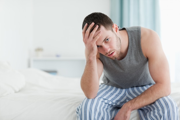 Tired man sitting on his bed