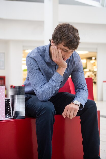 Tired man sitting in shopping mall