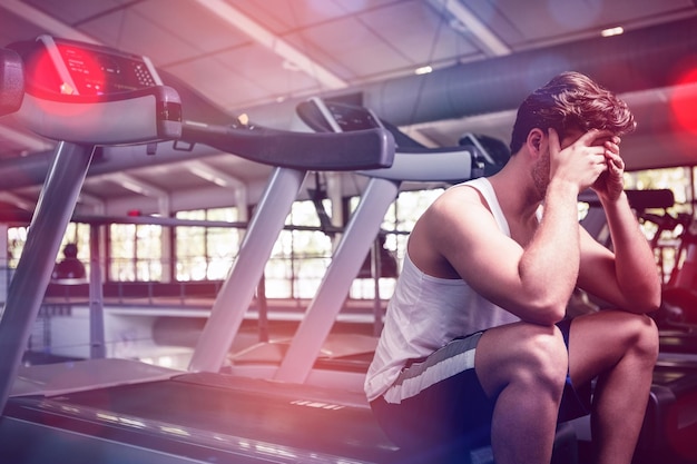 Tired man sitting on treadmill at gym