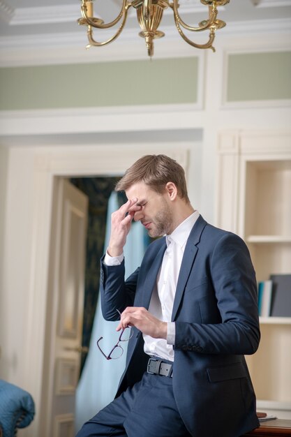 A tired man wearing a costume taking his eyeglasses off