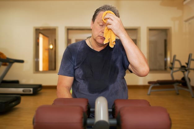 Tired man wiping sweat after workout