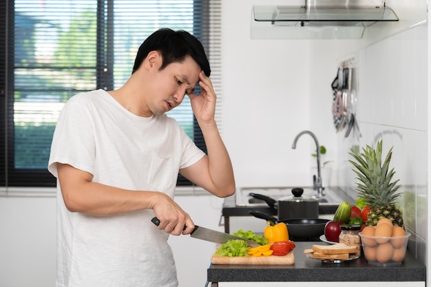 家の台所で野菜を調理する準備をしている疲れた男