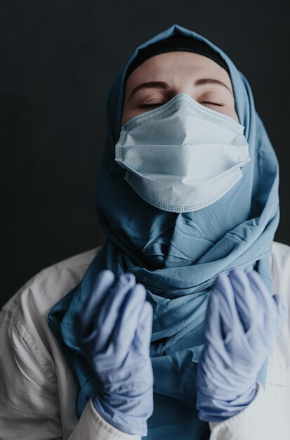 코로나바이러스의 전염병으로 인해 많은 환자를 받은 후 히잡을 쓰고 기도하는 지친 의료 종사자 의사 여성 이슬람 여성