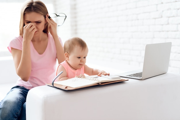 Photo tired mother with baby working and using laptop