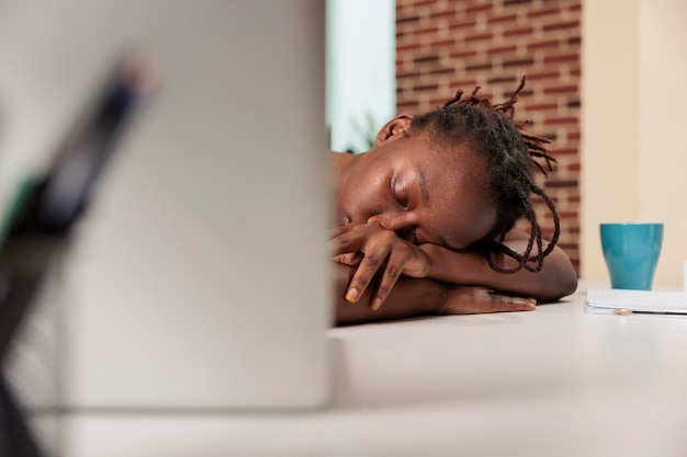 Foto impiegato stanco e oberato di lavoro che dorme sulla scrivania durante il giorno, lavoratore a distanza stressato assonnato, esaurimento professionale. studente sdraiato sulla scrivania, libero professionista che dorme sul posto di lavoro, concentrarsi sul viso