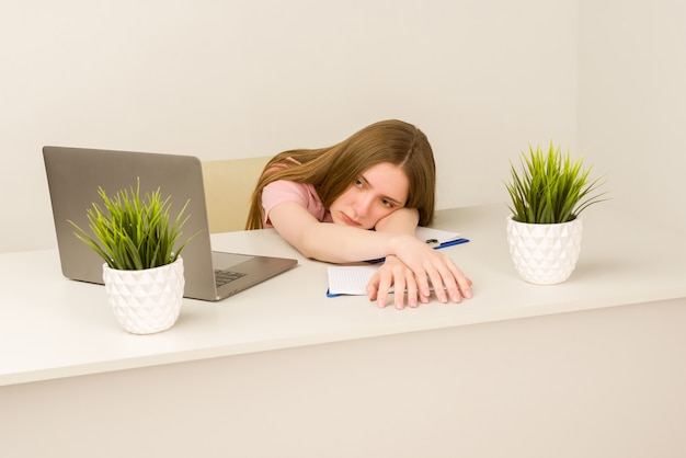 Tired overworked young intern woman working with a laptop in an office