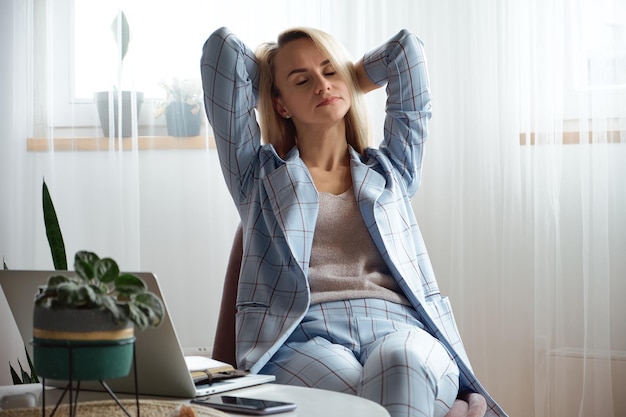 Tired overworked young woman in a suit sitting on a chair in the office