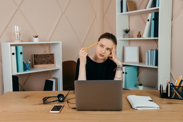 Tired overworking businesswoman at workplace in office, holding her head in hands