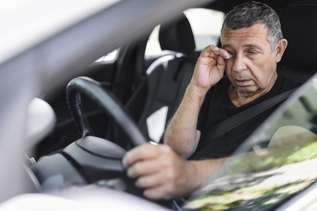 Photo tired pensioner dring in a car