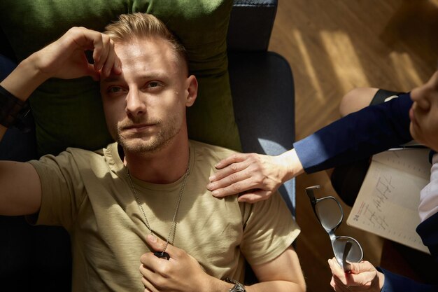 Photo tired pensive military man feeling worry and despair overhead view psychological trauma and ptsd treatment at therapy session