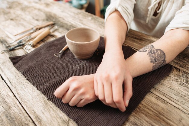 Tired potter hands near clay bowl table