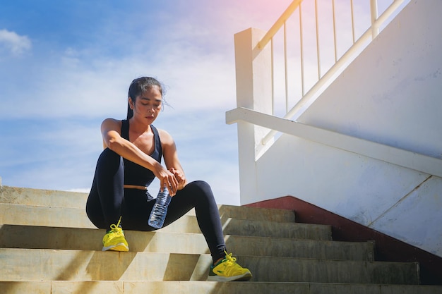 Photo tired runner woman with a bottle of electrolyte drink freshness after training outdoor workout